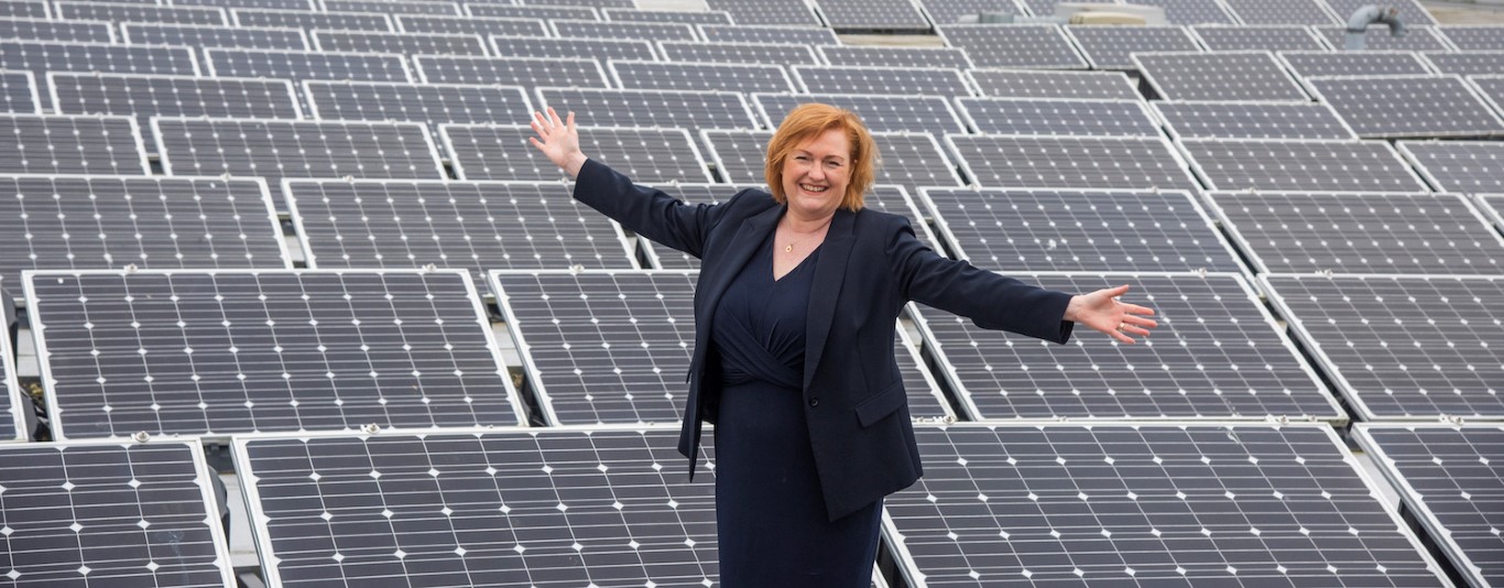Principal Angela Cox standing next to solar panels
