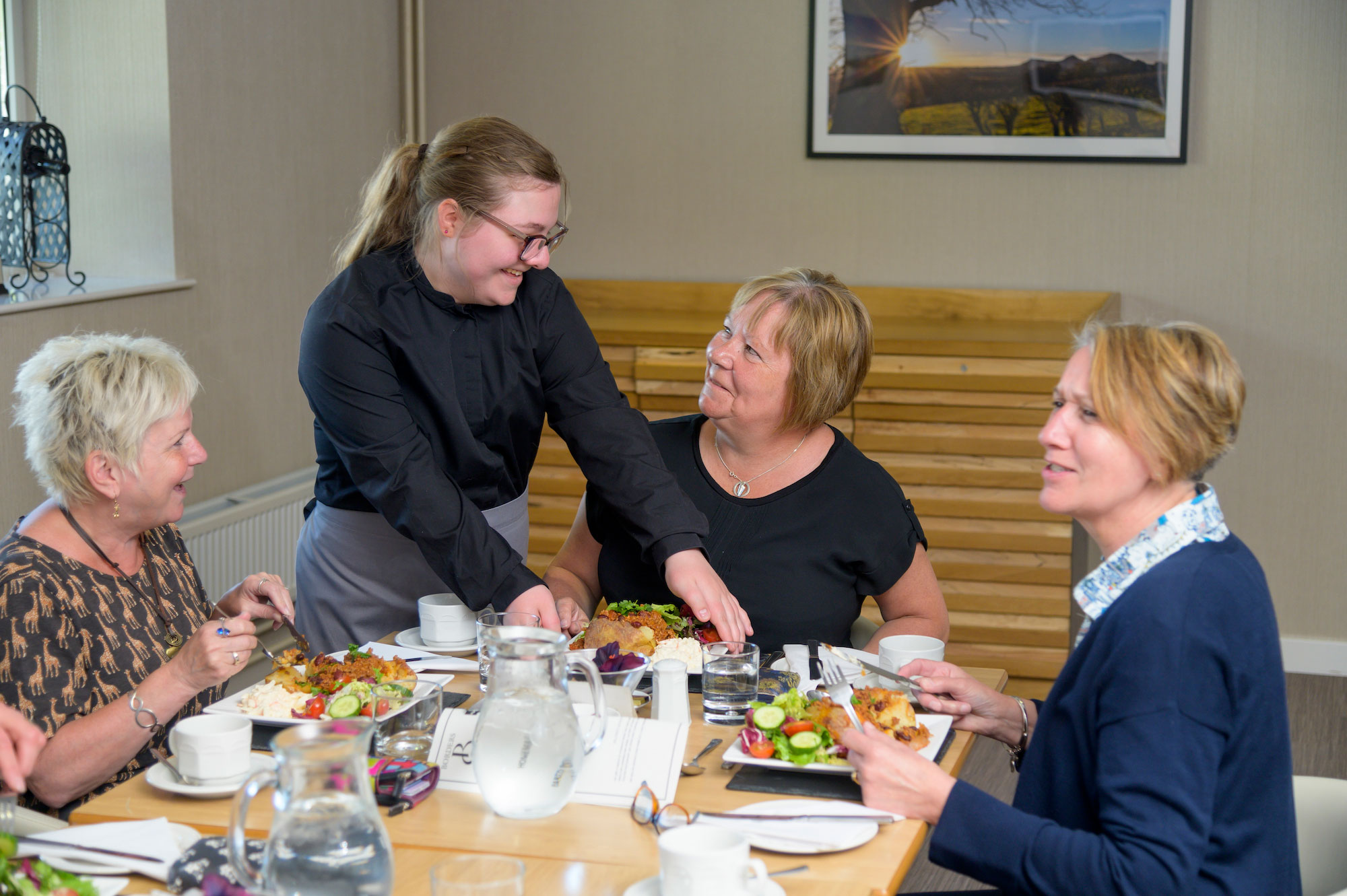 student serving a group of women in a cafe