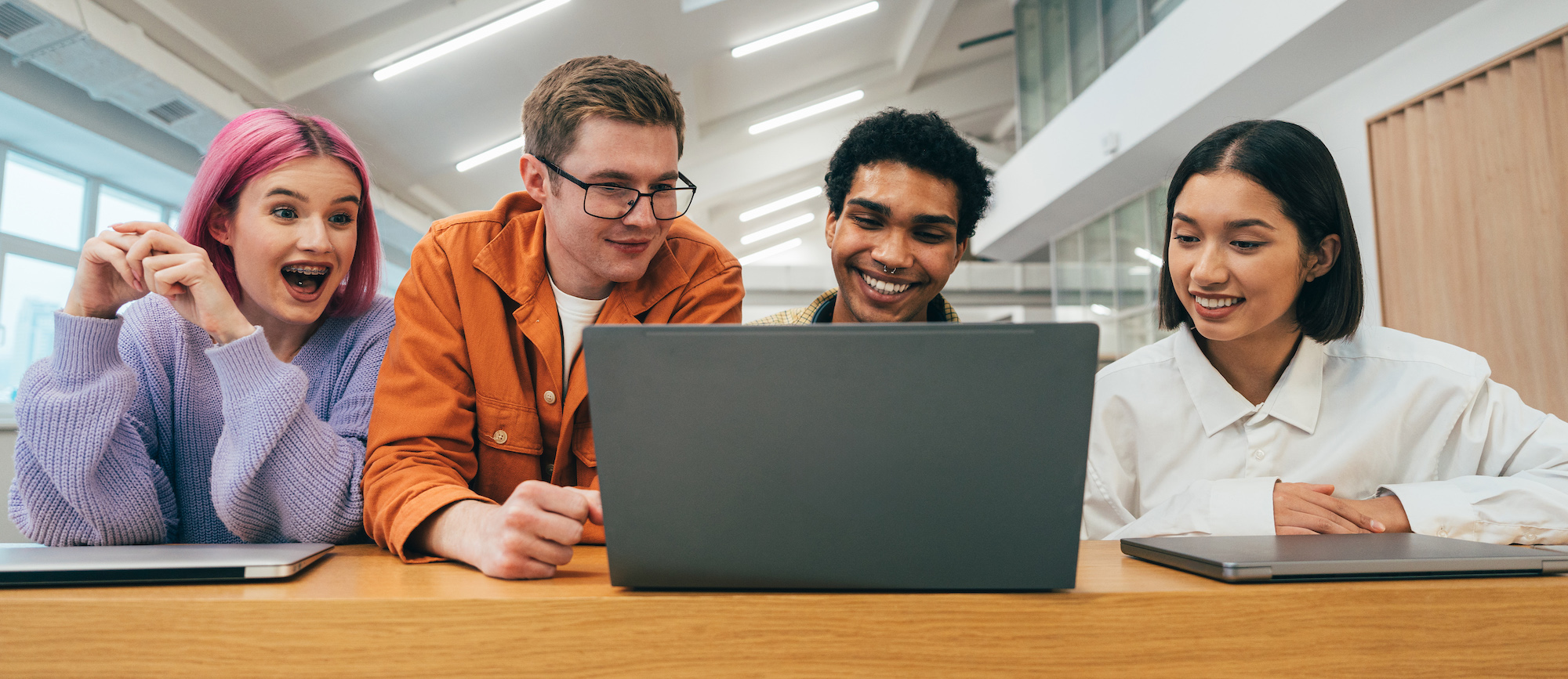 Four students using a laptop computer