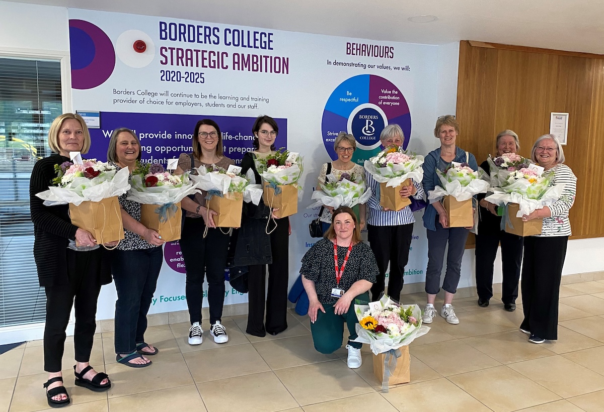 Group of students pictured standing with flower arrangements