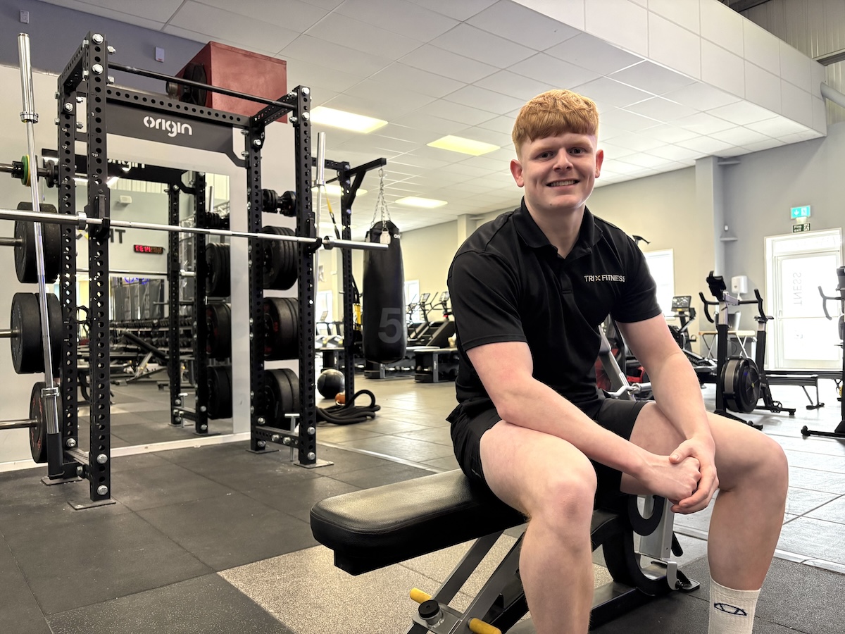 Photo of a fitness instructor sitting on a bench in a gym setting