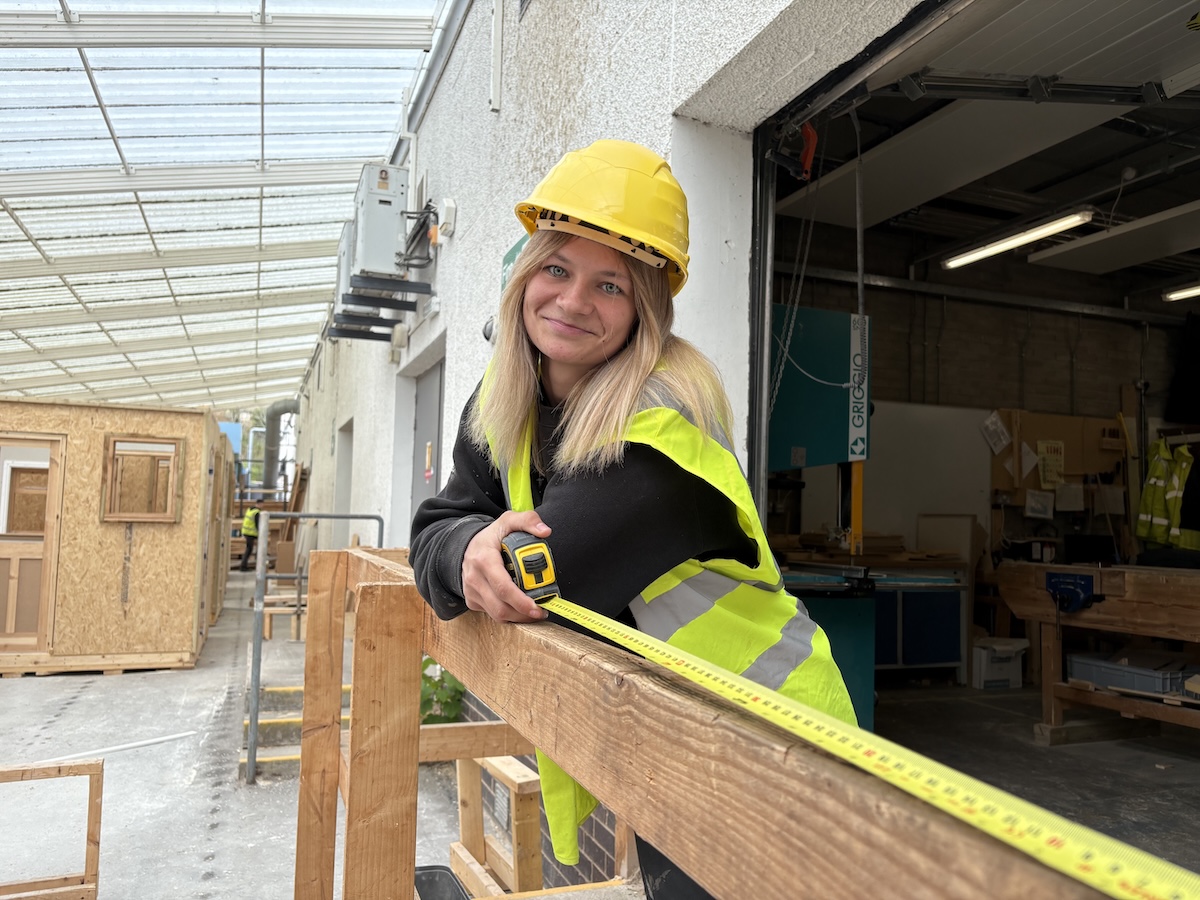 Photo of a female carpentry student standing in a workshop setting