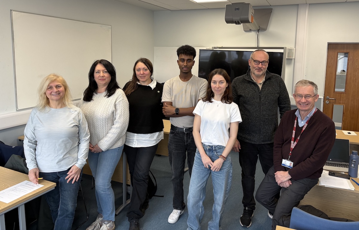 Group of staff and students standing in a classroom setting.